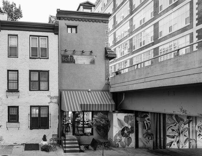 "South 24th Street and Walnut Street, Philadelphia" by James Abbott. An Inkjet Print depicting a storefront next to an overpass. Landscape, Cityscape, Black and White, Photograph. The Print Center