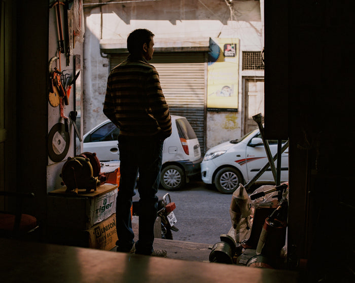 "Dukaan" By Saleem Ahmed.An Inkjet Print depicting a man looking out over a street. Photography, Color, Cityscapes, Urban Landscapes, Cars. The Print Center