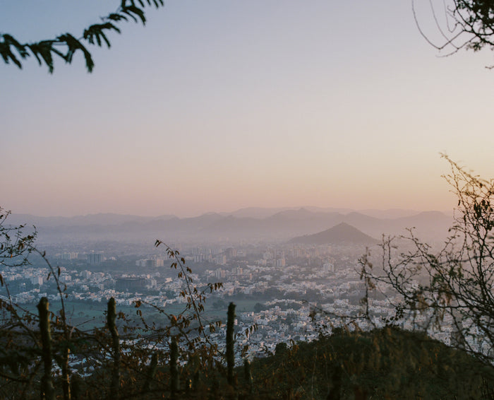 "Rajasthan" an inkjet print by Saleem Ahmed. depicts a view of a city wrapped in an early morning haze from the top of a hill. Landscape, Color Photography, Landscape, cityscape, nature, trees, sunrise, sunset, leaves, branches, mountains, clouds. The Print Center