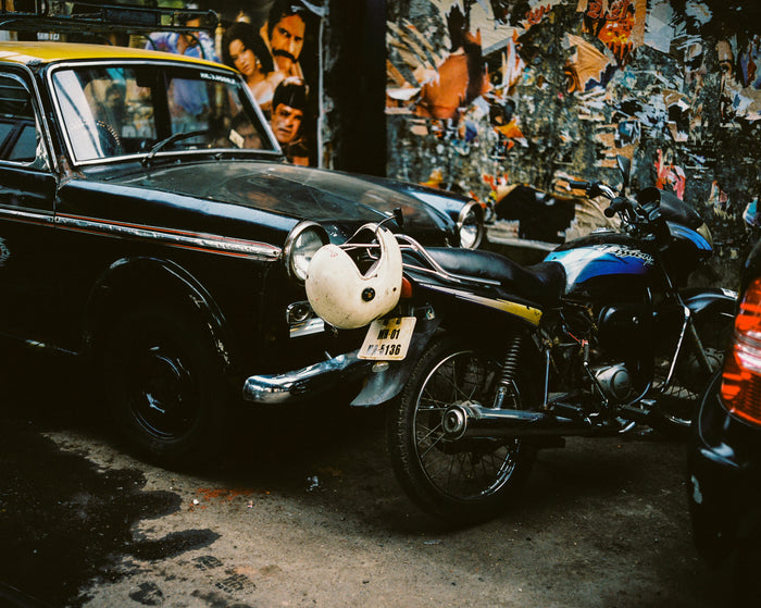 "Ambassador" by Saleem Ahmed. An Inkjet print depicting parked cars and a motorcycle against a poster covered wall. Photography, Color, Cityscapes, Urban. The Print Center